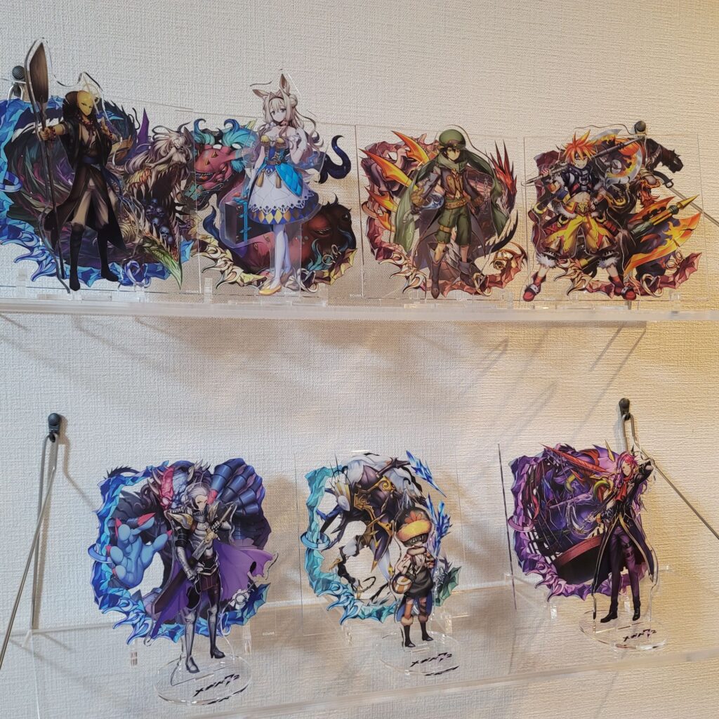 押しピン吊り下げ式のウォールラック上下二段にメギド72のアクリルスタンドが飾られている写真。
左上から、サレオス(カウンター)、ネフィリム(カウンター)、アモン(ラッシュ)、モラクス(ラッシュ)、ロノウェ(カウンター)、バラキエル、カスピエル(カウンター)