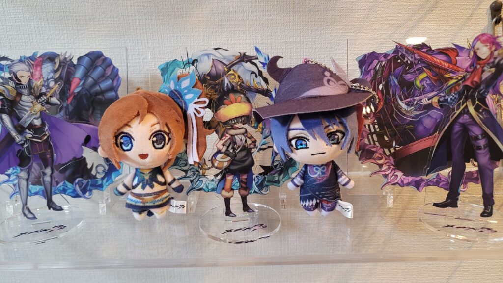 メギド72のアクリルスタンドとぬいぐるみの写真。アクリルスタンドは左からロノウェ（カウンター）、バラキエル、カスピエル（カウンター）。ぬいぐるみはプロメテウス（カウンター）、デカラビア（ラッシュ）。