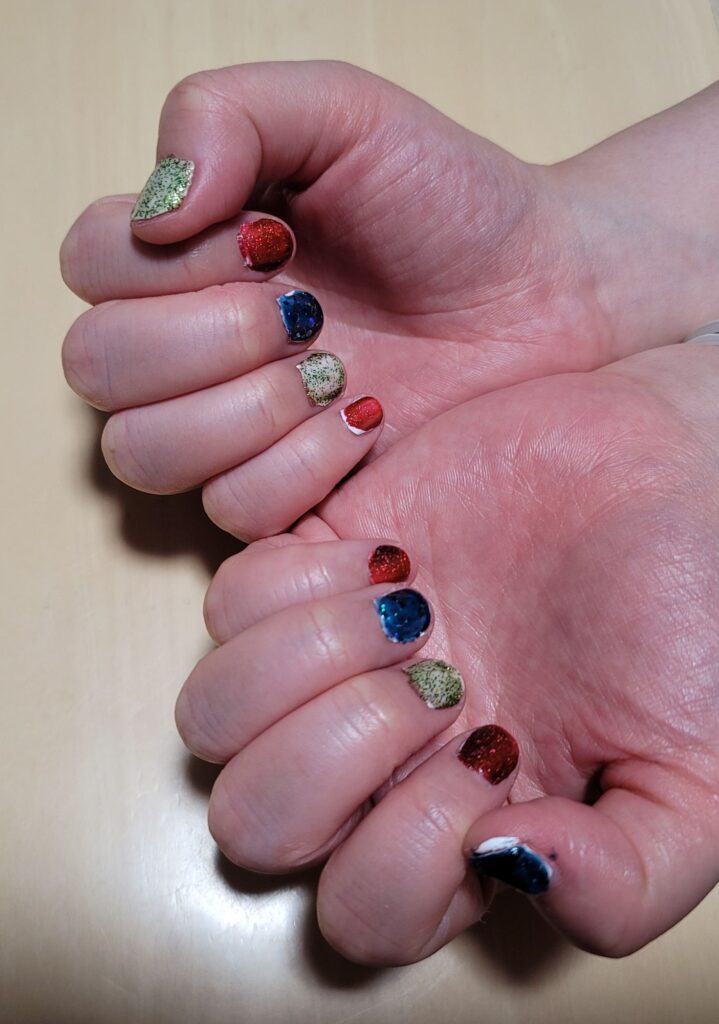 爪を赤と青と緑のマニキュアで塗った両手の写真